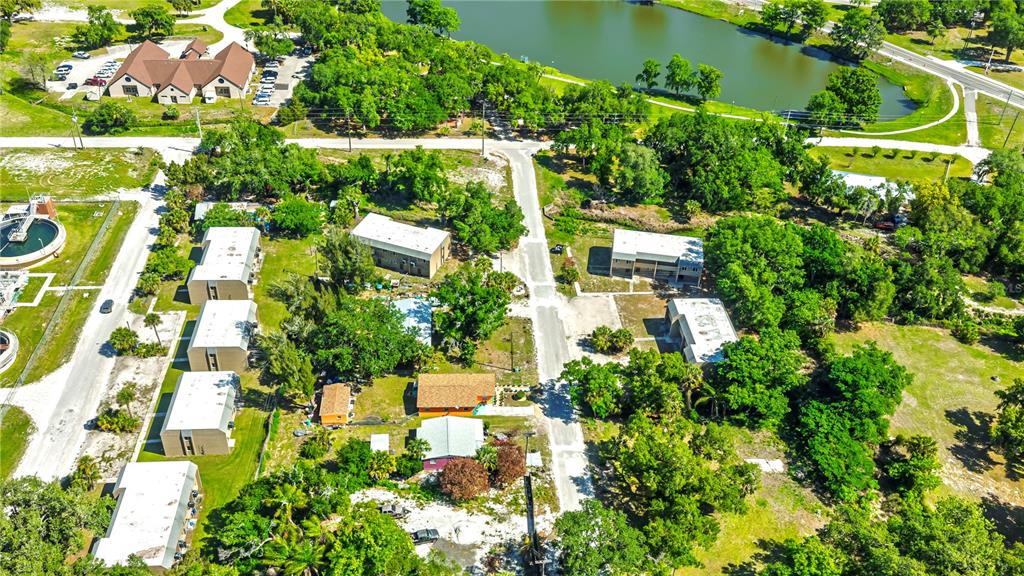 An aerial view shows several apartment buildings, a parking lot, and a pond — 111 JORDAN AVENUE, ARCADIA, FL