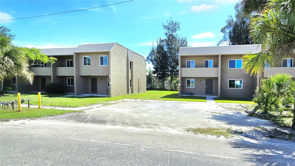 Two two-story apartment buildings stand behind a gravel parking area under a blue sky — 111 JORDAN AVENUE, ARCADIA, FL