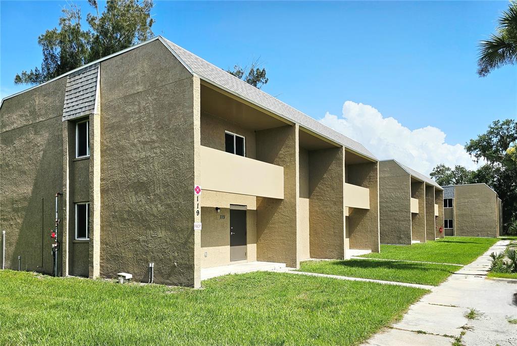 A two-story tan apartment building with recessed balconies and a concrete walkway in front — 111 JORDAN AVENUE, ARCADIA, FL