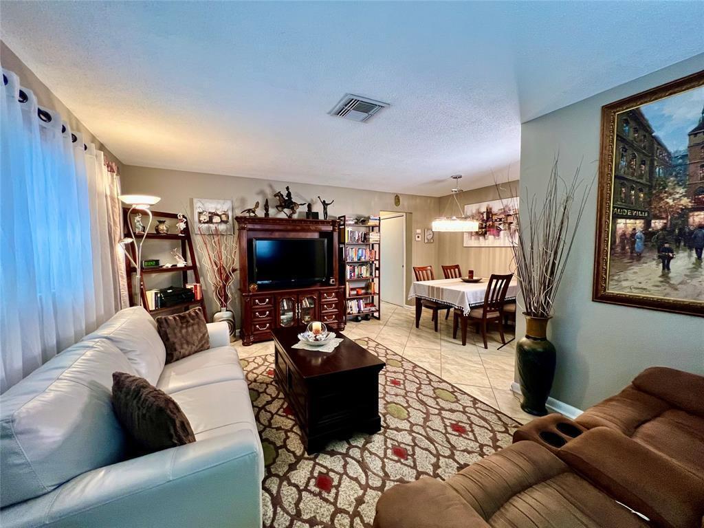 A living room with a white sofa, brown recliner, dark wood furniture, and tile flooring — 160 NE 8th Avenue # 1b, Hallandale Beach FL 33009, HALLANDALE BEACH, FL