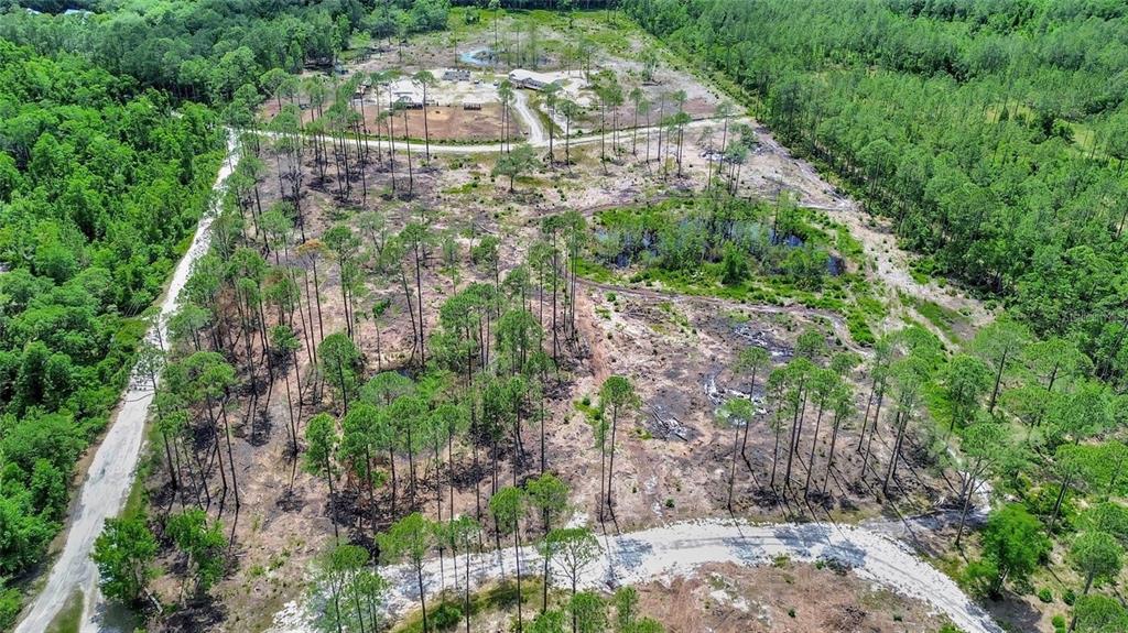 An aerial view shows a large, partially cleared wooded lot with dirt roads and ponds — MARSHVIEW DRIVE, DELAND, FL