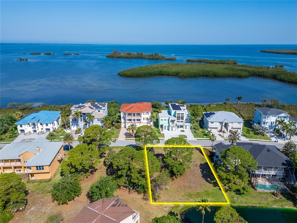 An aerial view shows a vacant residential lot outlined in yellow near a waterfront neighborhood — HARBOUR WATCH CIRCLE, TARPON SPRINGS, FL