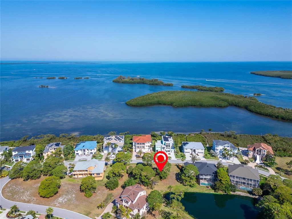 An aerial view shows a vacant lot marked with a red pin near the water — HARBOUR WATCH CIRCLE, TARPON SPRINGS, FL