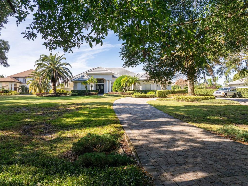 A paved driveway leads to a single-story house surrounded by trees and a lawn — 9002 PINNACLE CIRCLE, WINDERMERE, FL