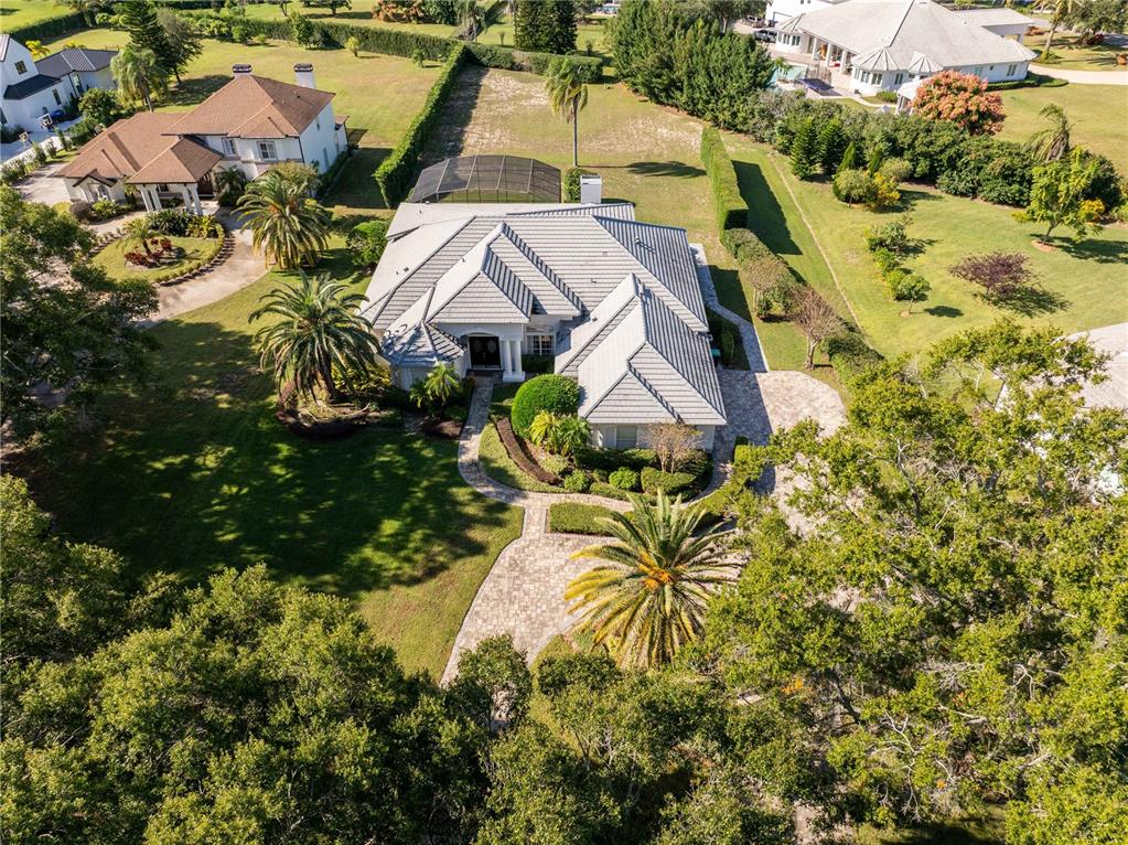 An aerial view shows a single-story house with a grey roof and a paved driveway — 9002 PINNACLE CIRCLE, WINDERMERE, FL