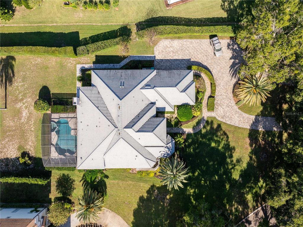 An aerial view shows a house with a gray roof, a screened-in pool, and a driveway — 9002 PINNACLE CIRCLE, WINDERMERE, FL