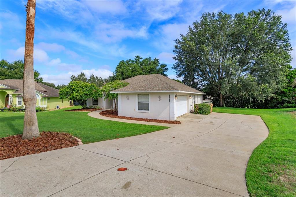 A white house with a concrete driveway and a large tree in the front yard — 11316 VIA MARI CAE COURT, CLERMONT, FL