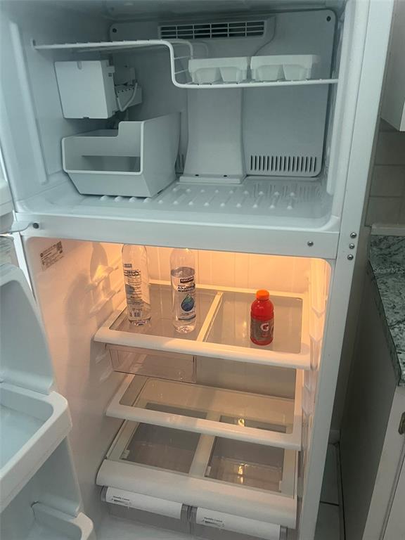 An open white top-freezer refrigerator with glass shelves and a few beverage bottles inside — 5205 DUBLIN PLACE, TAMPA, FL