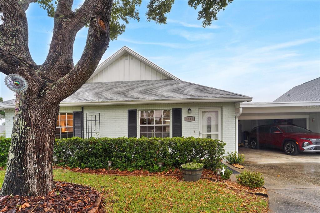 A single-story white brick house features a gray shingled roof, shutters, and a carport — 6642 DEVONSHIRE LANE, NEW PORT RICHEY, FL