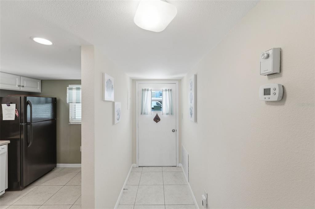 A tiled entryway leads to a white front door, with a kitchen visible to the left — 325 N CAUSEWAY UNIT D104, NEW SMYRNA BEACH, FL
