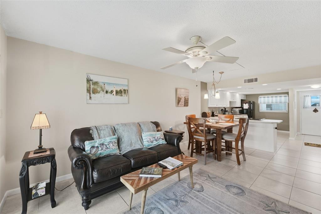 A living room with a leather sofa, wooden coffee table, and an adjacent dining area — 325 N CAUSEWAY UNIT D104, NEW SMYRNA BEACH, FL