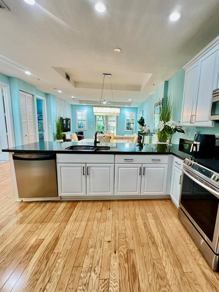 A kitchen features white cabinets, a dark granite island with bar seating, and light walls — 3120 E Latitude Circle E # 101s, Delray Beach FL 33483, DELRAY BEACH, FL