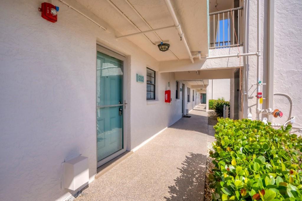 An outdoor walkway leads past a teal front door with a number 514 sign — 175 KINGS HIGHWAY UNIT 514, PUNTA GORDA, FL