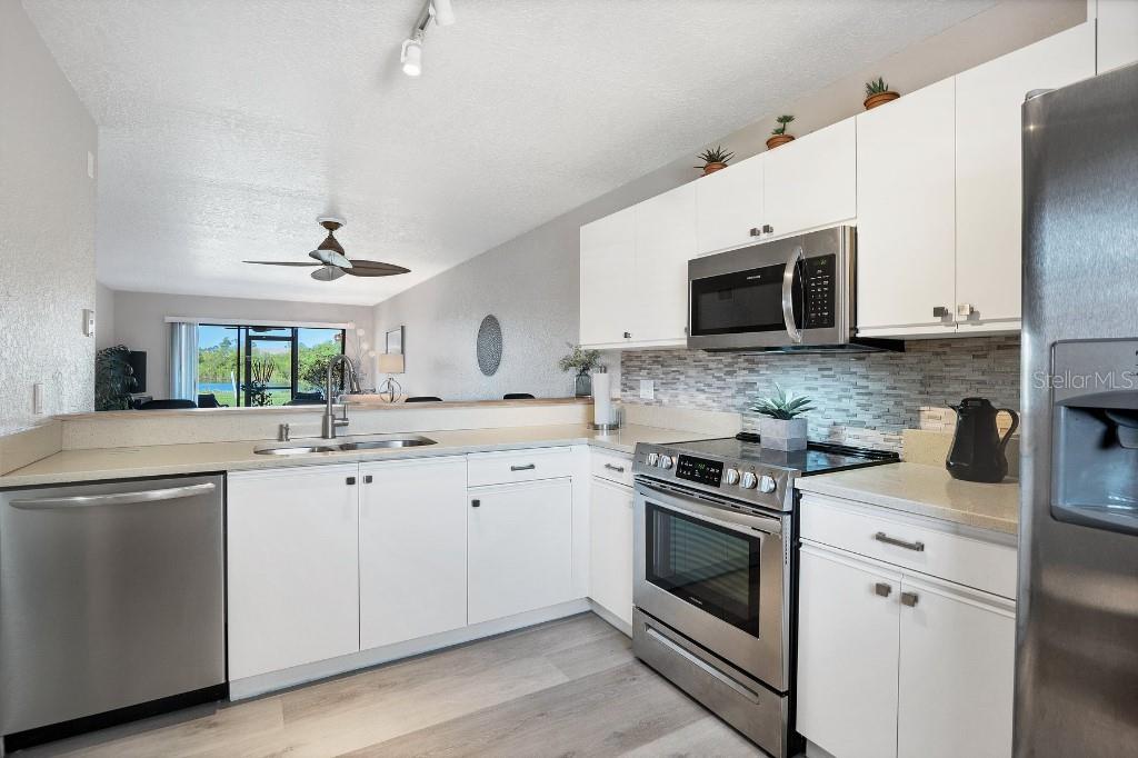 A kitchen with white cabinets, stainless steel appliances, and a view of a lake outside — 175 KINGS HIGHWAY UNIT 514, PUNTA GORDA, FL