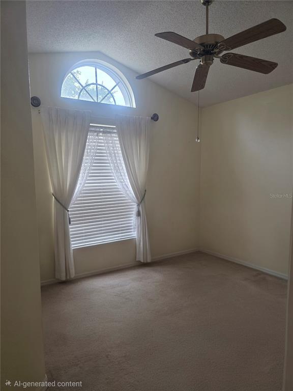 An empty room features beige carpet, a ceiling fan, and a window with white curtains — 7935 OAKSTONE COURT, ORLANDO, FL