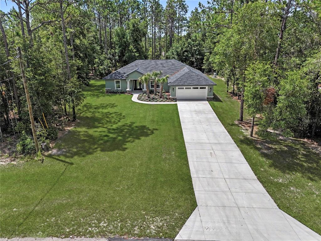 An aerial view shows a single-story house with a gray roof and a concrete driveway — 20638 SW 88 PLACE ROAD, DUNNELLON, FL