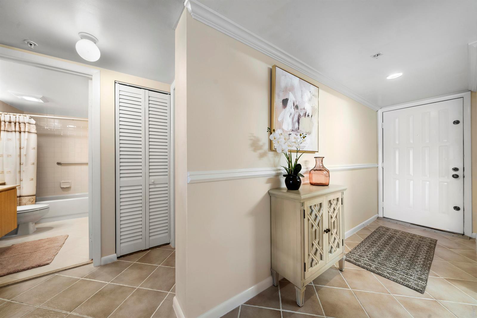 An entryway features tile flooring, a small cabinet, a wall painting, and an adjacent bathroom — 601 Seafarer Circle # 104, Jupiter FL 33477, JUPITER, FL