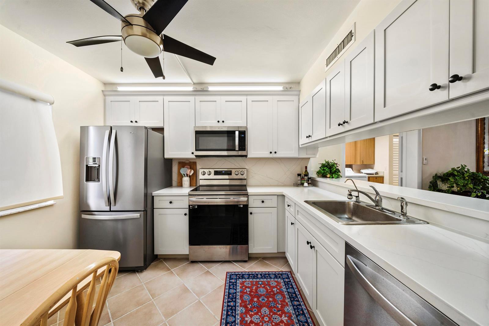 A kitchen features white cabinets, stainless steel appliances, a ceiling fan, and tile flooring — 601 Seafarer Circle # 104, Jupiter FL 33477, JUPITER, FL