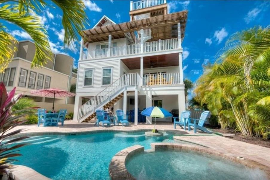 A three-story coastal home features a swimming pool, hot tub, and outdoor seating area — 117 WILLOW AVENUE, ANNA MARIA, FL