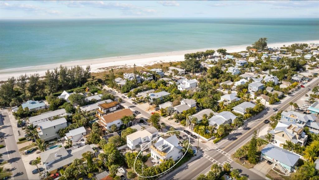An aerial view shows a white house near a beach with surrounding coastal homes — 117 WILLOW AVENUE, ANNA MARIA, FL