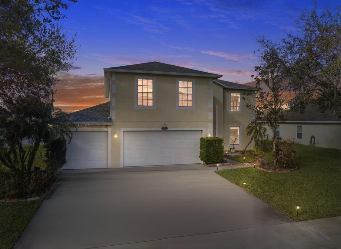 A two-story yellow house with a three-car garage sits next to a lake — 6052 Ridge Lake Circle, Vero Beach FL 32967, VERO BEACH, FL