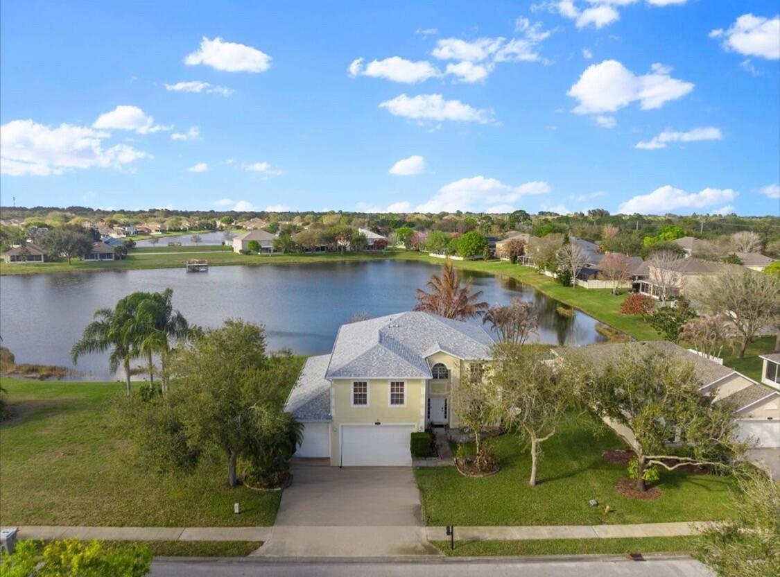 A two-story house with a three-car garage and a concrete driveway at dusk — 6052 Ridge Lake Circle, Vero Beach FL 32967, VERO BEACH, FL