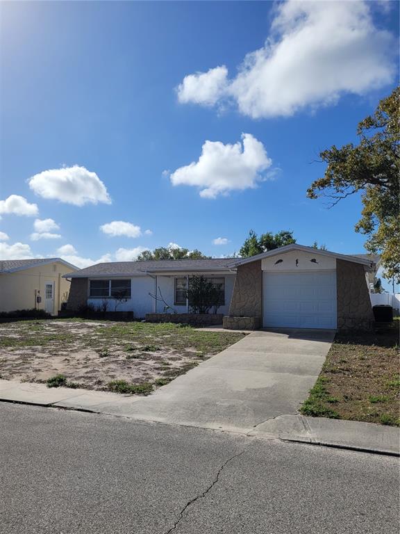 A single-story house with a white exterior, a front-facing garage, and a concrete driveway — 5814 LIDDELL DRIVE, NEW PORT RICHEY, FL