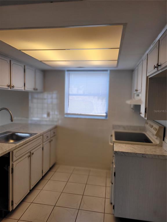 A kitchen features white cabinets, a window with blinds, and a large recessed ceiling light — 5814 LIDDELL DRIVE, NEW PORT RICHEY, FL
