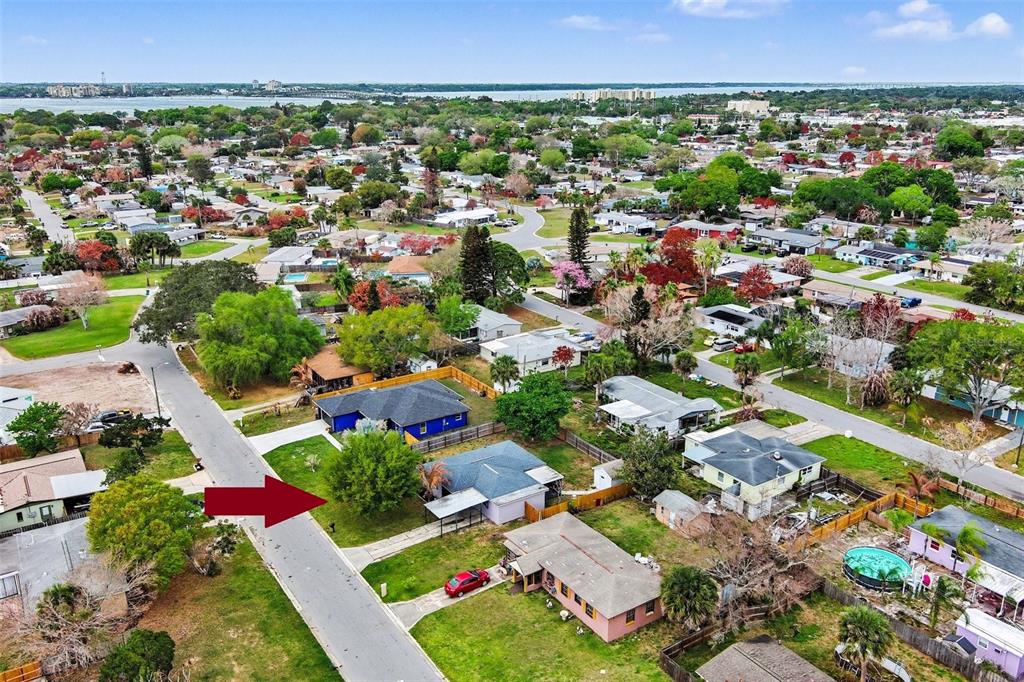 An aerial view shows a residential neighborhood with a red arrow pointing to a house — 514 PALM AVENUE, MERRITT ISLAND, FL