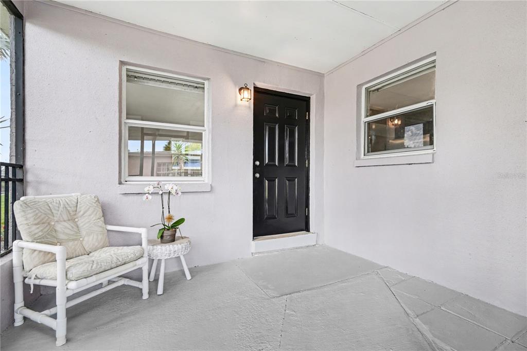 A covered porch features a black front door, two windows, and a white wicker chair — 514 PALM AVENUE, MERRITT ISLAND, FL