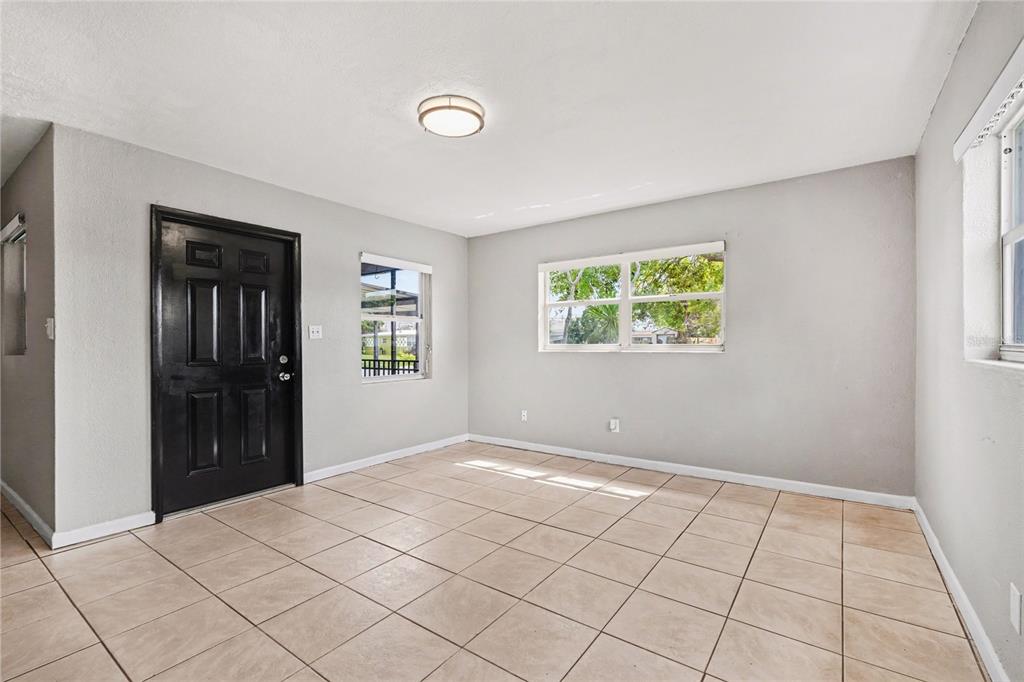 A room with light grey walls, beige tile flooring, a black door, and two windows — 514 PALM AVENUE, MERRITT ISLAND, FL