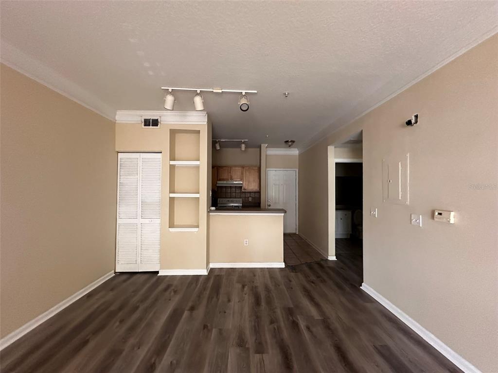 An open living area features wood-look flooring, a kitchen with a breakfast bar, and shelving — 4207 S DALE MABRY HIGHWAY UNIT 2103, TAMPA, FL