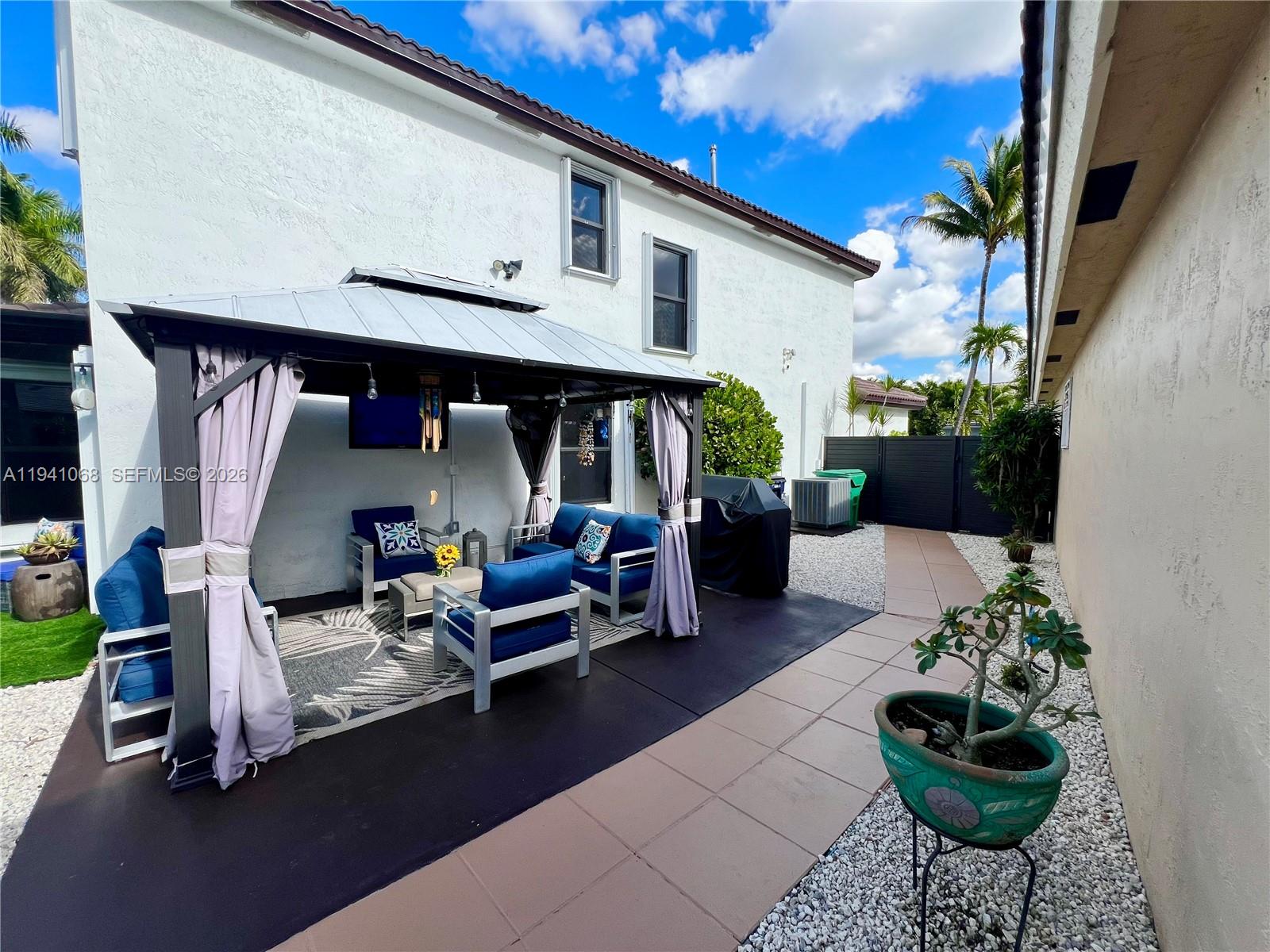 A backyard patio features a metal gazebo with outdoor seating and a paved walkway — 8618 SW 161st Pl, Miami FL 33193, MIAMI, FL