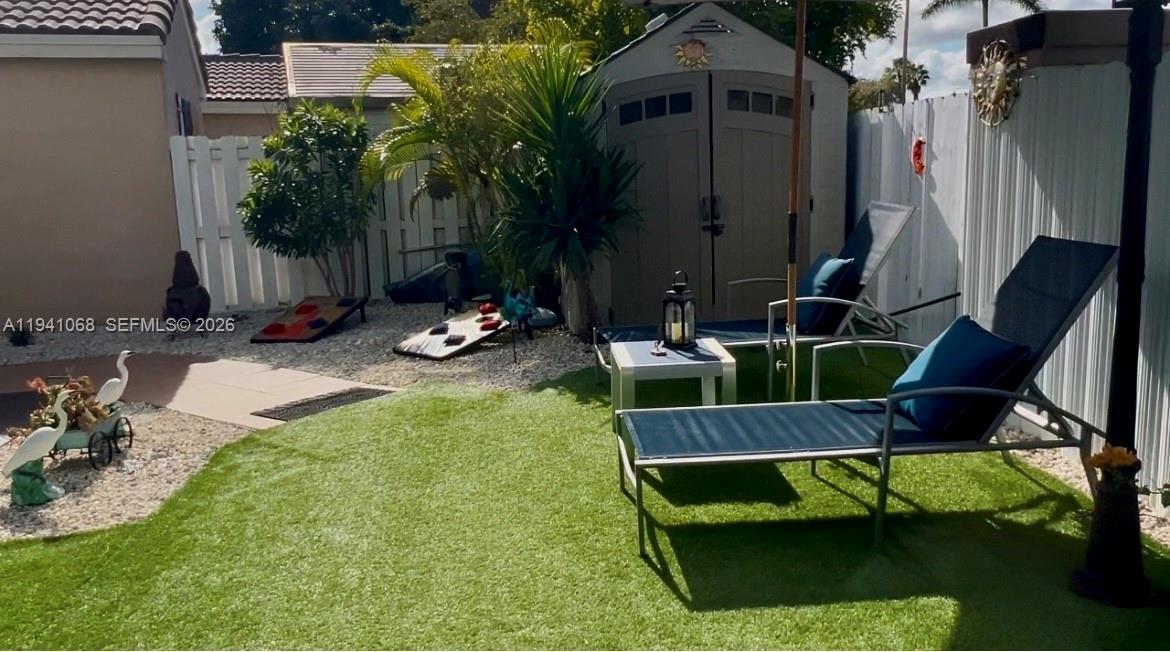A backyard features artificial turf, two lounge chairs, a storage shed, and a cornhole set — 8618 SW 161st Pl, Miami FL 33193, MIAMI, FL