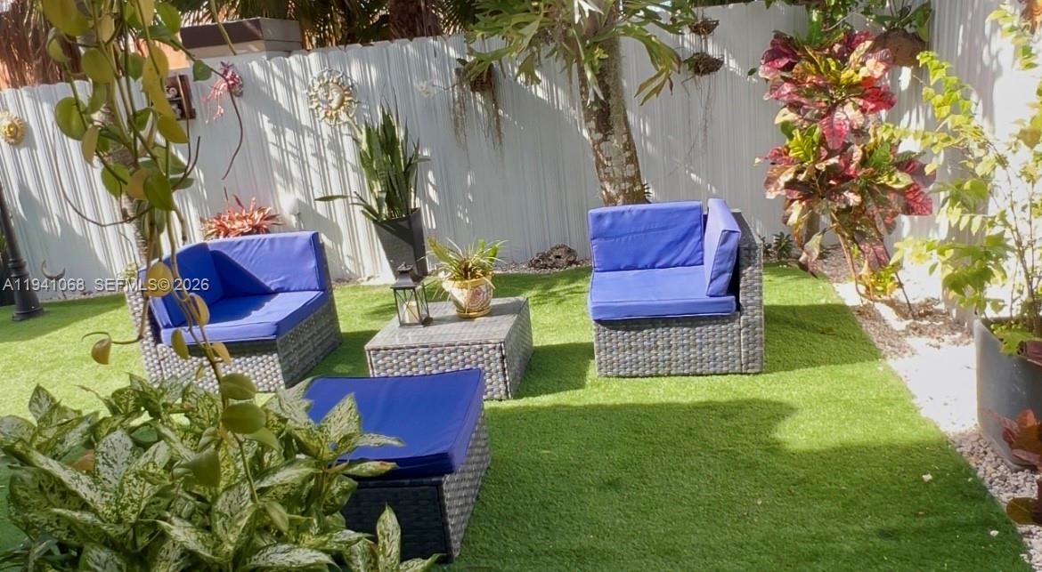 A small outdoor patio features artificial turf, wicker furniture with blue cushions, and potted plants — 8618 SW 161st Pl, Miami FL 33193, MIAMI, FL