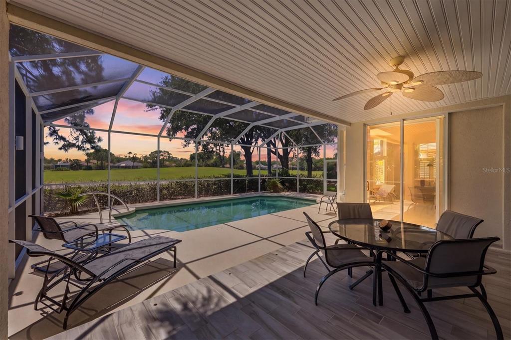 A covered patio features a swimming pool, outdoor furniture, and a view of a grassy field — 7316 SAINT GEORGES WAY, UNIVERSITY PARK, FL