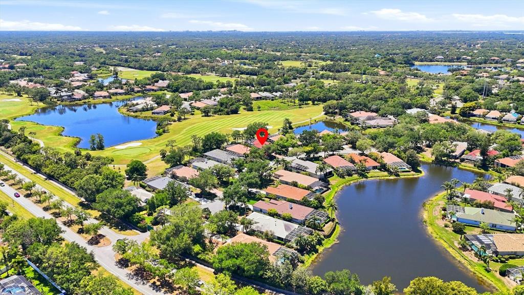 An aerial view shows a residential neighborhood with houses, lakes, and a golf course — 7316 SAINT GEORGES WAY, UNIVERSITY PARK, FL