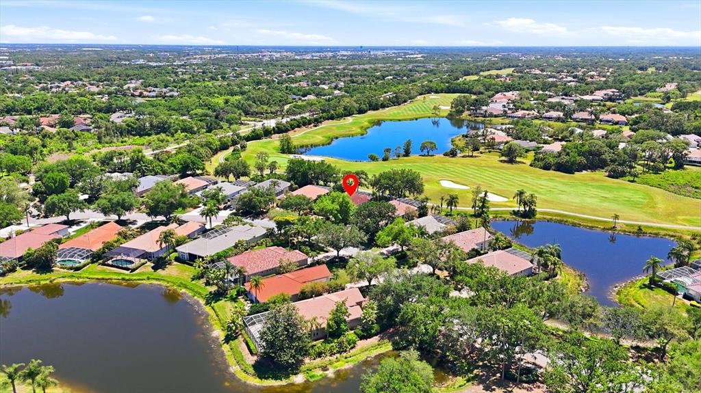 An aerial view shows a residential neighborhood with houses surrounding two lakes and a golf course — 7316 SAINT GEORGES WAY, UNIVERSITY PARK, FL