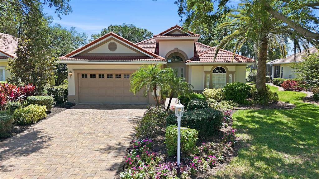 A single-story house with a tiled roof, a brick driveway, and a landscaped front yard — 7316 SAINT GEORGES WAY, UNIVERSITY PARK, FL