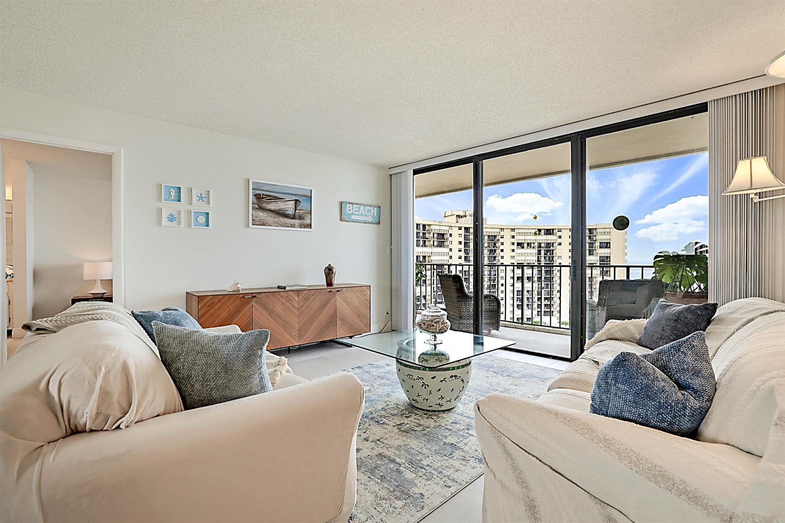 A living room features two beige sofas, a wooden sideboard, and a balcony with ocean views — 100 Ocean Trail Way # 1003, Jupiter FL 33477, JUPITER, FL