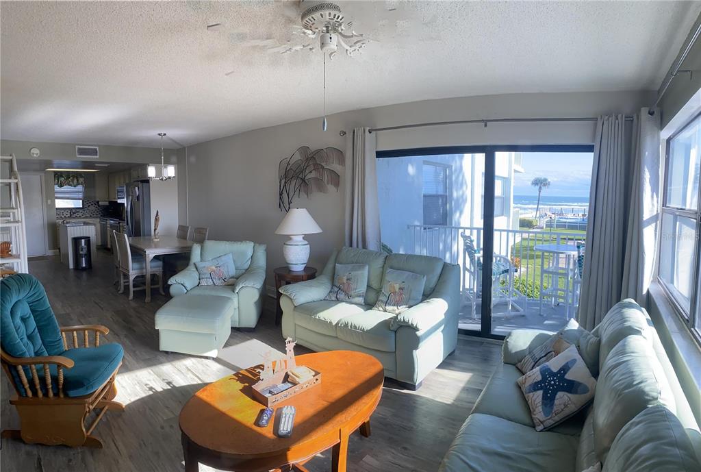 A living room with light-colored furniture, a wooden coffee table, and a view of the ocean — 1571 S ATLANTIC AVENUE UNIT 201, NEW SMYRNA BEACH, FL