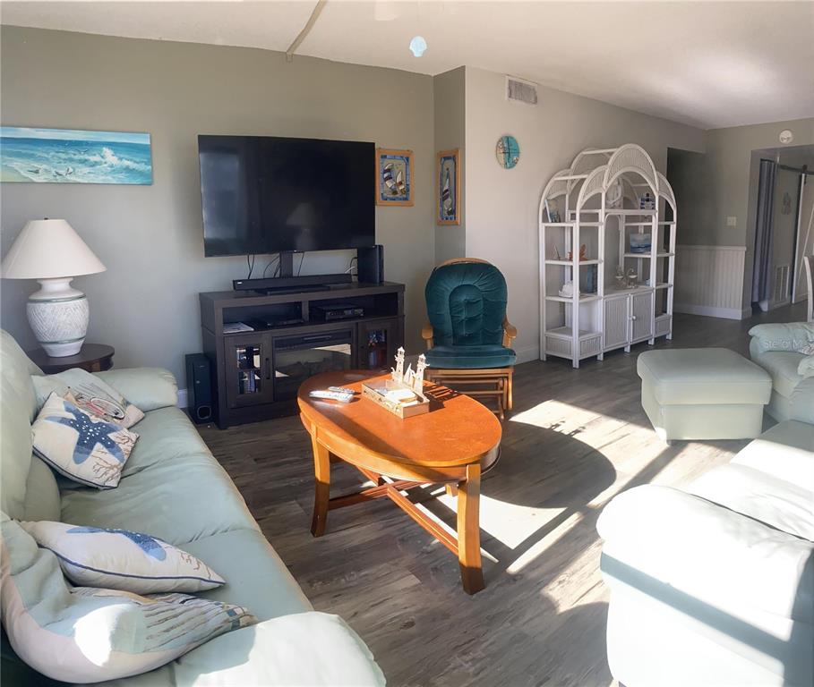 A living room features a light green sofa, a television console, and a wooden coffee table — 1571 S ATLANTIC AVENUE UNIT 201, NEW SMYRNA BEACH, FL