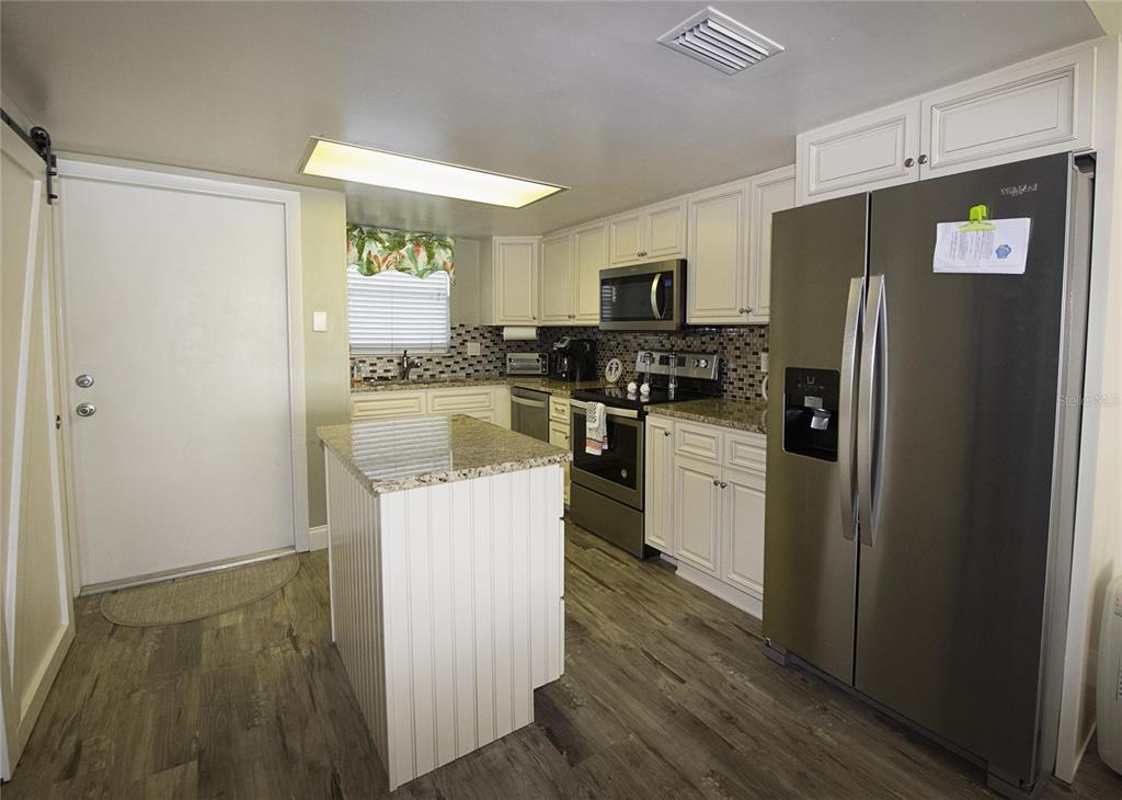A kitchen features white cabinets, granite countertops, stainless steel appliances, and a central island — 1571 S ATLANTIC AVENUE UNIT 201, NEW SMYRNA BEACH, FL