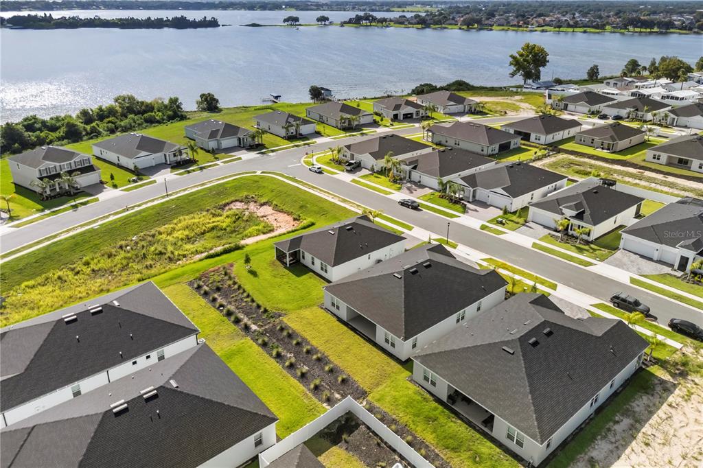 An aerial view shows a suburban neighborhood of single-family homes near a large lake — 1714 UPLAND LANE, WINTER HAVEN, FL