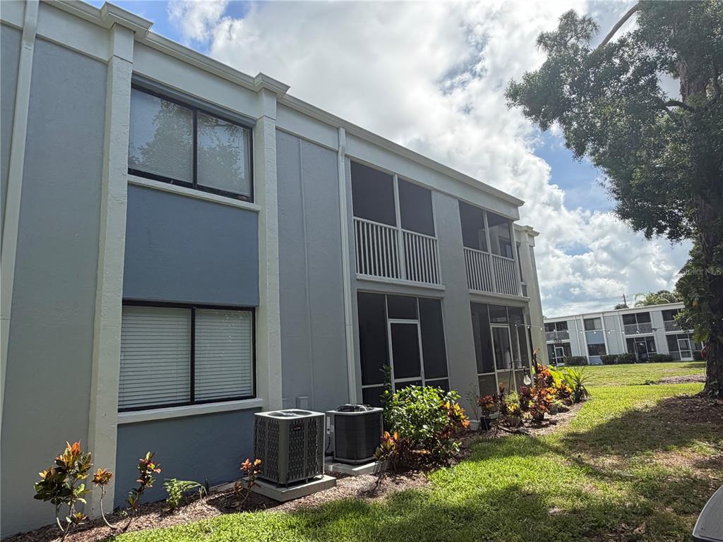 The exterior of a two-story apartment building features gray siding, screened balconies, and air conditioning units — 5310 26TH STREET W UNIT 2904, BRADENTON, FL