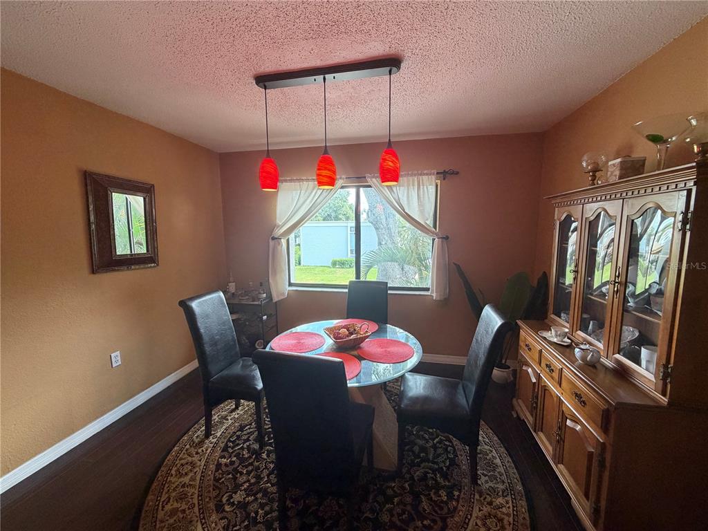 A dining room features a glass table, black chairs, a wooden hutch, and red pendant lights — 5310 26TH STREET W UNIT 2904, BRADENTON, FL