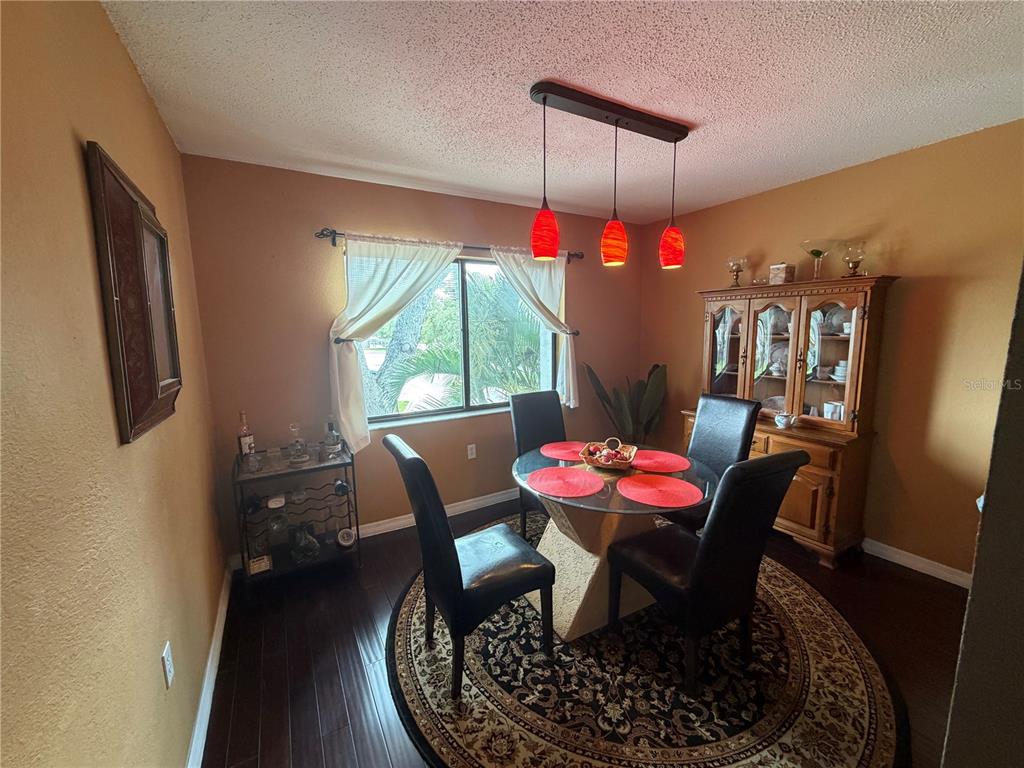 A dining room features a glass-topped table, four black chairs, and a wooden hutch — 5310 26TH STREET W UNIT 2904, BRADENTON, FL