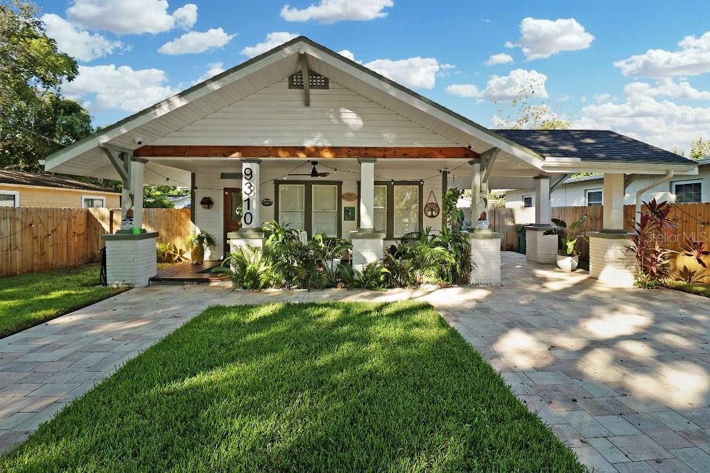 A single-story house with a front porch, white brick columns, and a paved driveway — 9310 N 18TH STREET, TAMPA, FL
