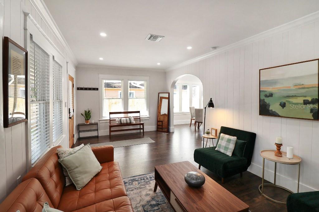 A living room with white shiplap walls, dark wood floors, and a leather sofa — 9310 N 18TH STREET, TAMPA, FL