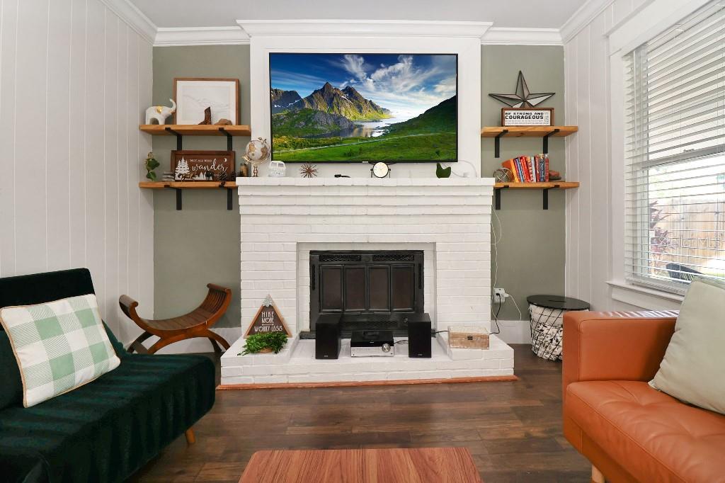 A living room features a white brick fireplace, wall-mounted television, and built-in wooden shelving — 9310 N 18TH STREET, TAMPA, FL